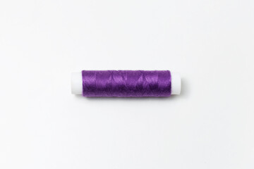 Fototapeta na wymiar Close-up of purple thread spool isolated on white background. Very peri color.