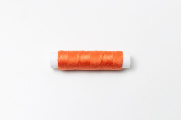 Close-up of orange thread spool isolated on white background.