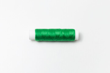 Close-up of green thread spool isolated on white background.
