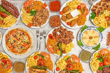Plates with Turkish, Arabic and Mediterranean food with fried chicken, falafel, chickpea hummus, tomato salad, croquettes, kebab, lamb chops, red lentils, pepper, basmati rice