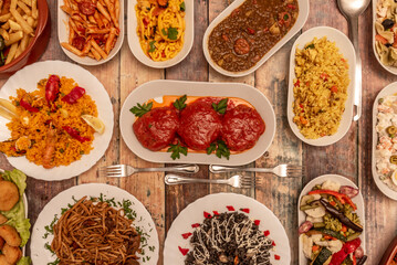 Set of assorted dishes of Spanish food with stuffed peppers, lentils stewed with chorizo, black rice with squid, Valencian paella, Russian salad and Chinese noodles