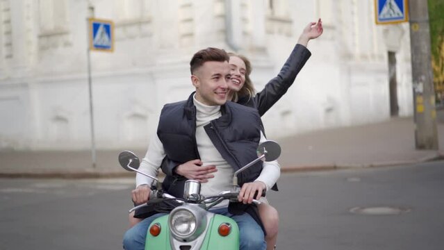 A married couple rides a motor scooter around the city