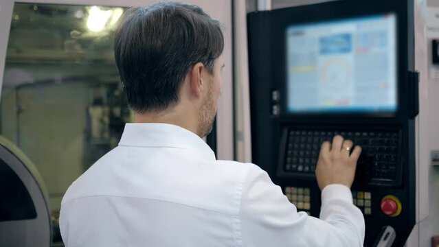 An engineer at an industrial plant. A worker controls the operation of a CNC milling machine. Tablet computer in hand. Drill manufacturing plant.