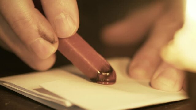 A seal stamp customary in the 18th century being used to secure a letter with sealing wax melted by candle flame.