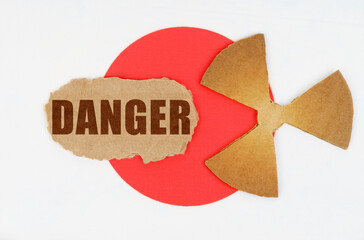 On the flag of Japan, the symbol of radioactivity and torn cardboard with the inscription - Danger