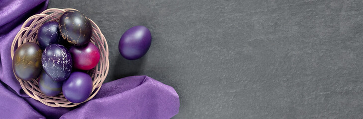 Black nest with painted eggs with silk. Festive Easter banner with branches. Concept design.