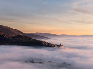 Drone view of Assisi Umbria Italy above a sea of fog at sunset