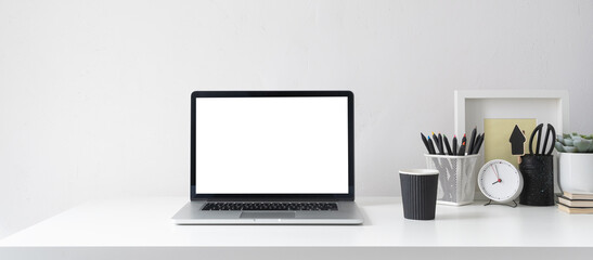 Desk with laptop screen, desk objects, office supplies, books, and plant on bright background.