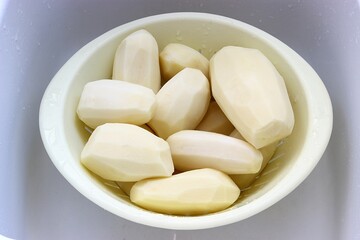 Fresh raw potatoes peeled and cleaned in a colander. Selective focus