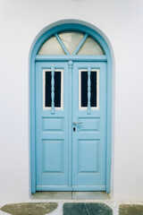 Old blue wooden door against clear white wall, Greece