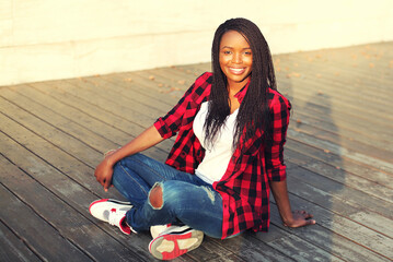 Portrait of happy smiling young african woman in casual in the city