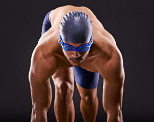 Make the laps count. Studio shot of a handsome swimmer ready to dive off the starting block.
