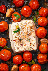 Oven-baked feta cheese with cherry tomatoes and herbs close-up.