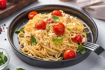 A portion of fetapasta on a gray background. Spaghetti with feta and cherry tomatoes.