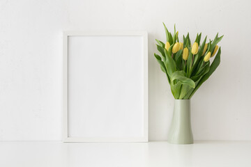 White desk with minimal vase with bunch of tulips against white wall...