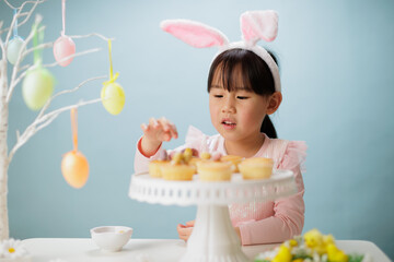 young girl making easter craft against plain background