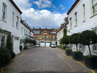 London, England. Horbury mews view. Street view, old houses, cobblestone, plants in pot, decoration. Picturesque spot. “Horbury mews 1878” is written on the house opposite.