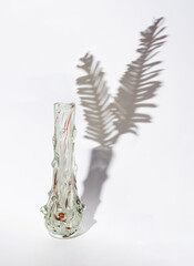 transparent empty vase on white background with shadows of topical palm leafs. creative abstract minimal composition.