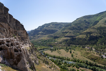 Naklejka premium monastery in the mountains of georgia where there are caves and passages along the mountain, above them there is a blue sky.