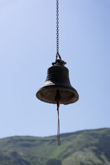 Fototapeta premium a large metal bell set on a string and hanging over a blue sky background.