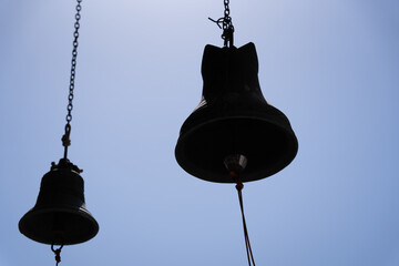 a large metal bell set on a string and hanging over a blue sky background.