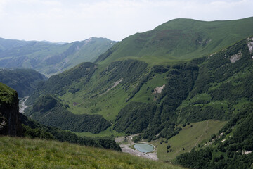 the Kazbegi mountain ranges in Georgia are green and have a clear sky above them.