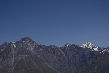 dramatically dark gray mountains with a bit of white snow on the tops, behind which a dark blue sky opens