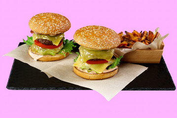 two Big burgers and sweet potato isolated on black stone plate. rose background. close up