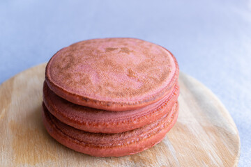 pila de 3 hot cakes esponjosos sabor fresa integral sobre base de madera circular y fondo claro