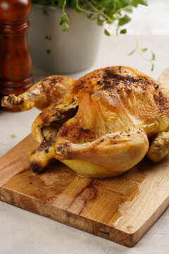 whole roasted chicken with glazed crispy skin on wooden board