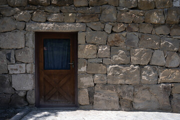 Fototapeta na wymiar stone building with a small wooden door with a window