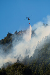 Forest fires, helicopters working through the intense smoke to control the fire.