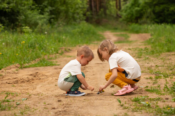 Little boy and girl play outdoors in the forest in summer