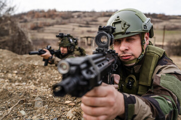 Two men soldiers holding position in the battle war zone aiming rifles dogs of war professional mercenaries or volunteers special forces on a mission attacking or defending enemy copy space