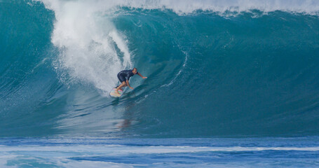 Surfer surfing big ocean barrel tube wave at Pipeline in north shore of Hawaii's Oahu island pro...