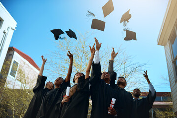Goodbye college, hello career. Shot of a group of young students throwing their hats in the air on graduation day.