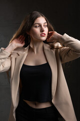 Fototapeta premium Portrait of a young brunette with long hair in the studio. Dramatic photo in dark colors.