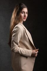 Portrait of a young brunette with long hair in the studio. Dramatic photo in dark colors.