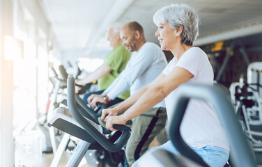 Fit seniors in diversity group on stationary fitness bikes in the gym - Powered by Adobe