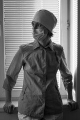 Naklejka premium A woman doctor stands near the hospital window. Black and white photo.