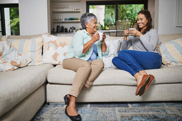 Chatting up a storm. Shot of a young woman and her mother catching up on the sofa while drinking...