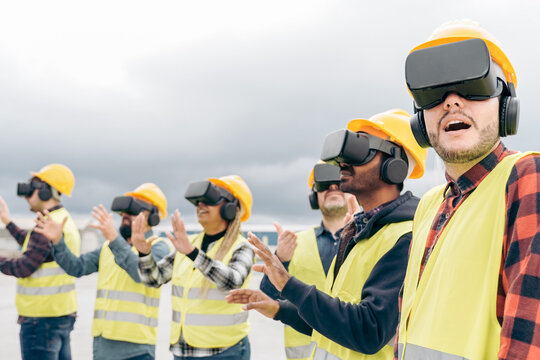 Multiracial team of industrial workers using virtual reality headsets at shipping cargo port - Metaverse and freight logistic concept - Focus on right man face
