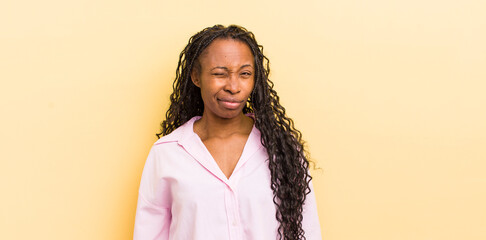 black pretty woman looking happy and friendly, smiling and winking an eye at you with a positive...