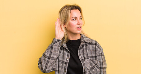 blonde caucasian woman looking serious and curious, listening, trying to hear a secret conversation...
