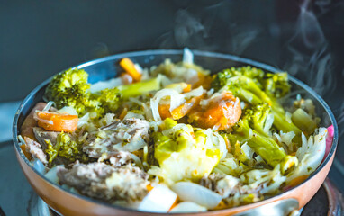 Mixed vegetables dinner, home cooked on a frying pan, steaming vegetables mixed with meat.