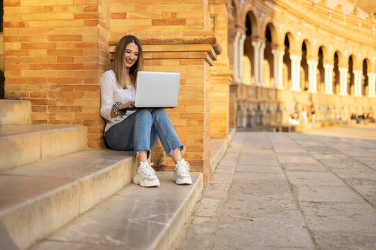 Young blonde woman working and studiying with a laptop outside