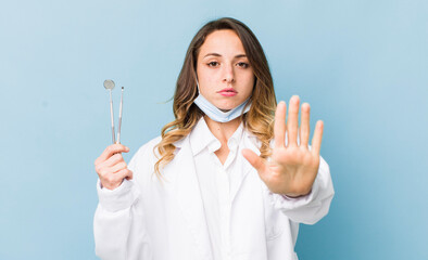 pretty woman looking serious showing open palm making stop gesture