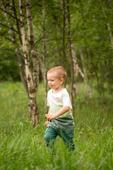 Cute boy in the forest against the background of grass summertime