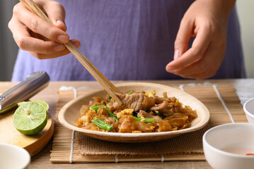 Fototapeta na wymiar Thai food (Pad See Ew), Stir fried rice noodles with soy sauce, egg, kale and pork eating by use chopsticks