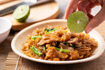 Thai food (Pad See Ew), Stir fried rice noodles with soy sauce, egg, kale and pork eating with lime